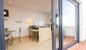 A modern kitchen with a dining area, featuring a bar counter, chairs, and a table.