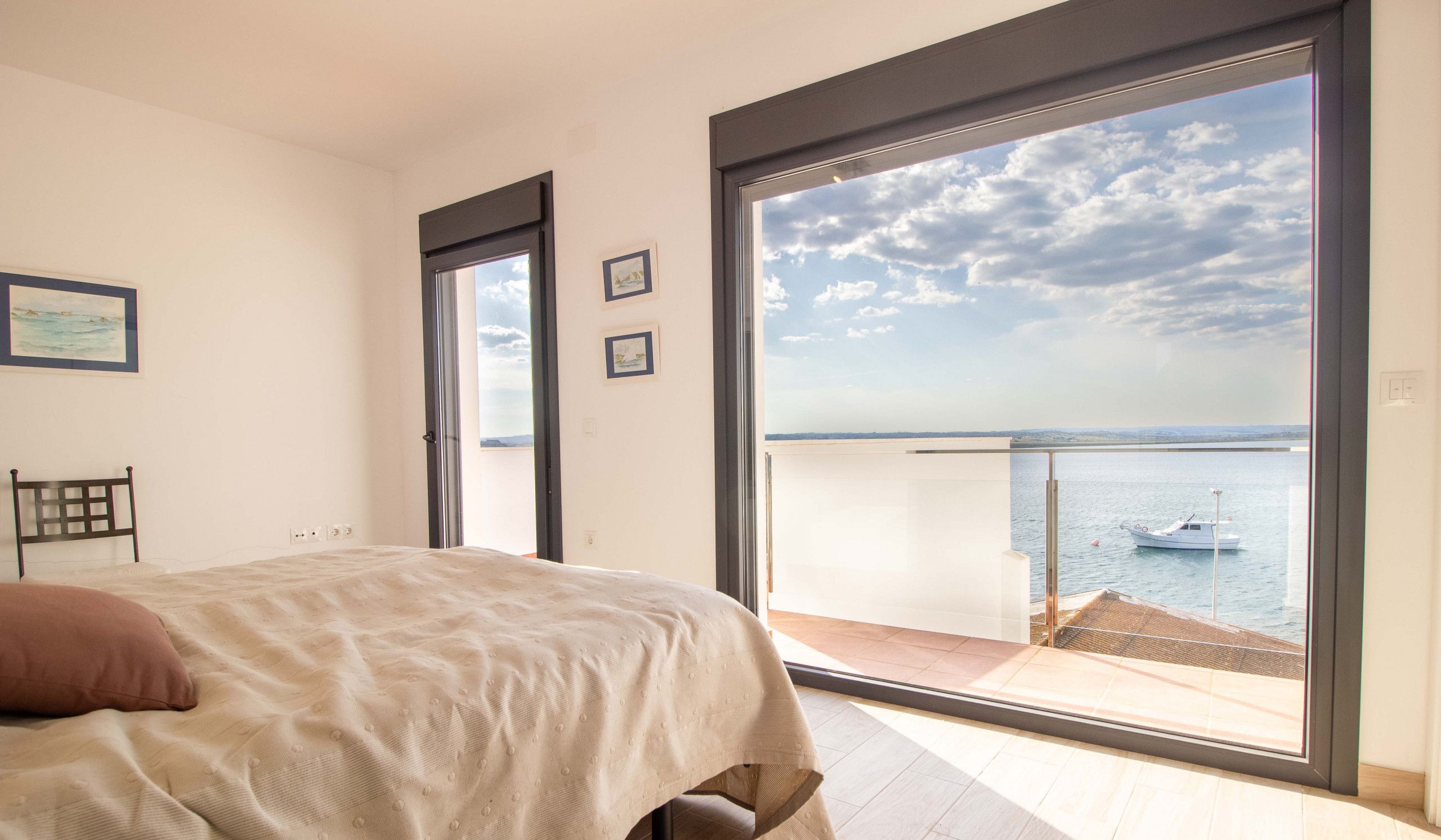 Une chambre avec une grande fenêtre donnant sur la mer et sur un bateau.