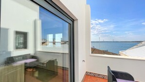 A modern room with a large glass window overlooking a beach and a bridge. - Apartment 4 bedrooms Center of Ayamonte with stunning Views DEK01 (Ayamonte)