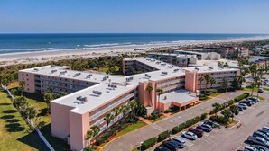 A multi-story hotel with a rooftop pool and a beach view.