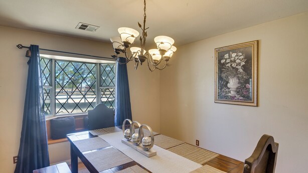 A dining room with a wooden table, blue curtains, a chandelier, and a framed artwork on the wall. - Spacious Lancaster Family Ranch - BBQ & Patio (Lancaster)