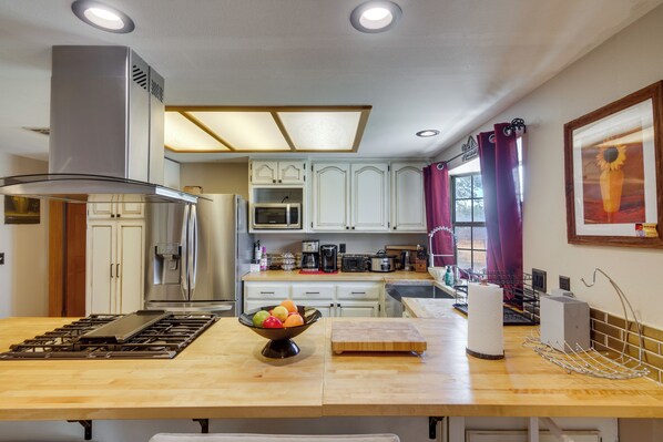 A modern kitchen with stainless steel appliances, a wooden countertop, and a bowl of fruit.