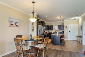 Una cocina amplia con una isla central, sillas de madera con cojines coloridos y una mesa de comedor.