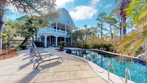 A large house with a pool, surrounded by trees and a paved walkway. - Let Camelot become your escape from realty. (St. George Island)
