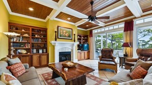 A spacious living room with a fireplace, bookshelves, and comfortable seating. - Let Camelot become your escape from realty. (St. George Island)