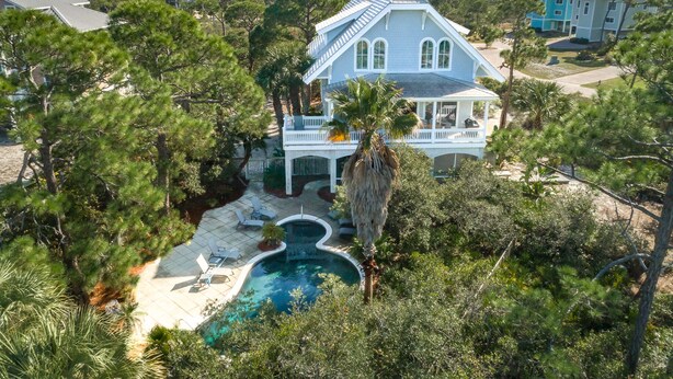 A large house with a pool, surrounded by trees and a view of the ocean. - Let Camelot become your escape from realty. (St. George Island)