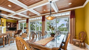 A dining area with a long table, wooden chairs, and a chandelier. - Let Camelot become your escape from realty. (St. George Island)