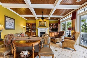A cozy living room with a fireplace, bookshelves, and comfortable seating. - Let Camelot become your escape from realty. (St. George Island)