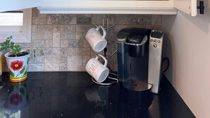 Una cocina con un armario que contiene cristalería, platos y una cafetera.