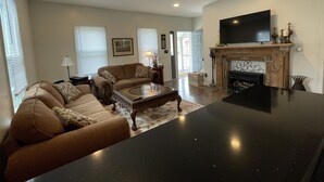 Una sala de estar con un conjunto de sofá, una mesa de centro, una chimenea y un televisor montado en la pared.