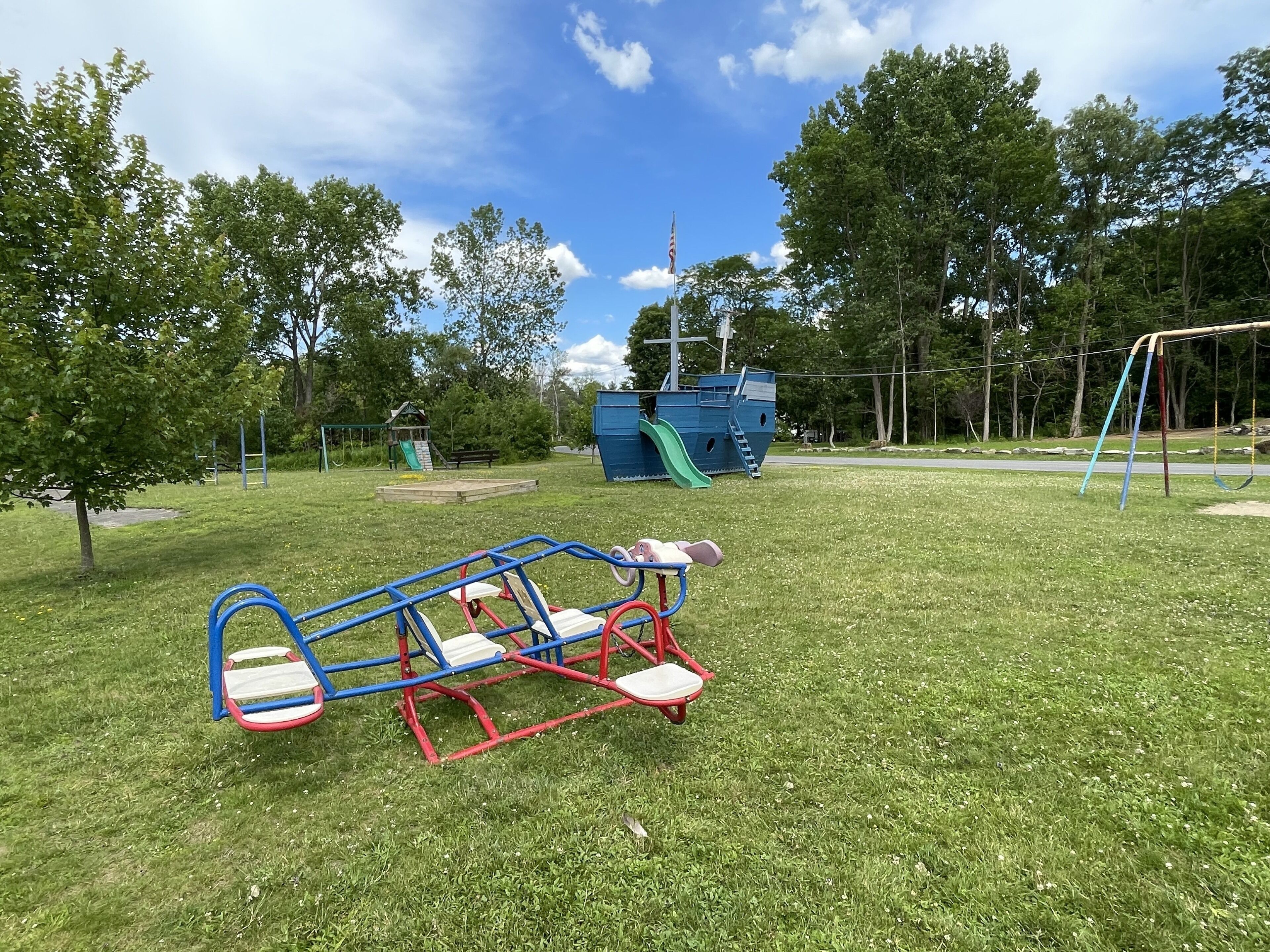 A playground with a seesaw, slide, and swing set.