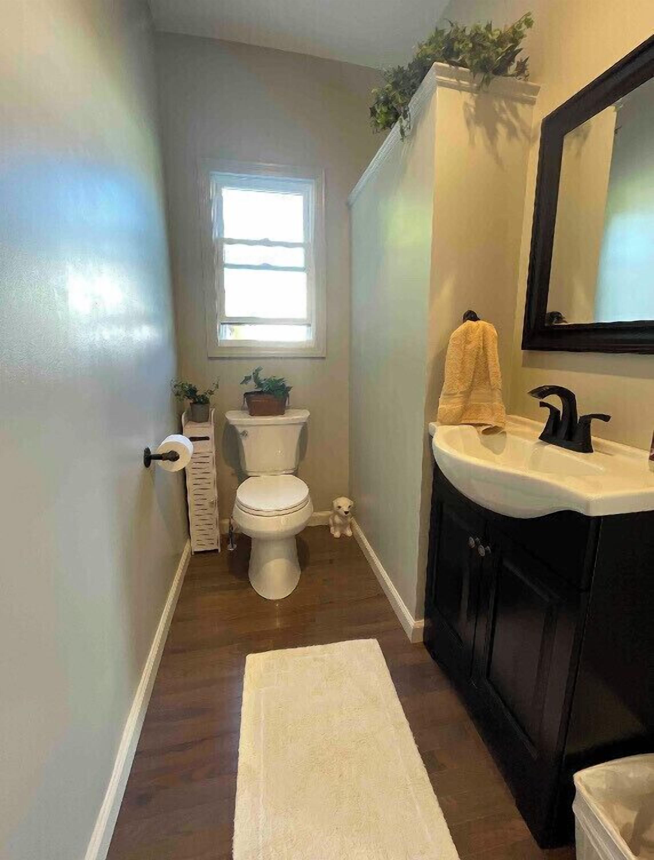 Een kleine badkamer met toilet, wastafel en raam.