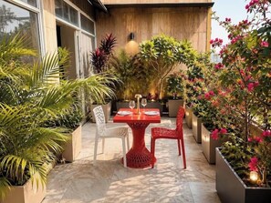 An outdoor patio with a table and chairs, surrounded by potted plants and flowers. - Staybook Hotel Aira  (New Delhi)