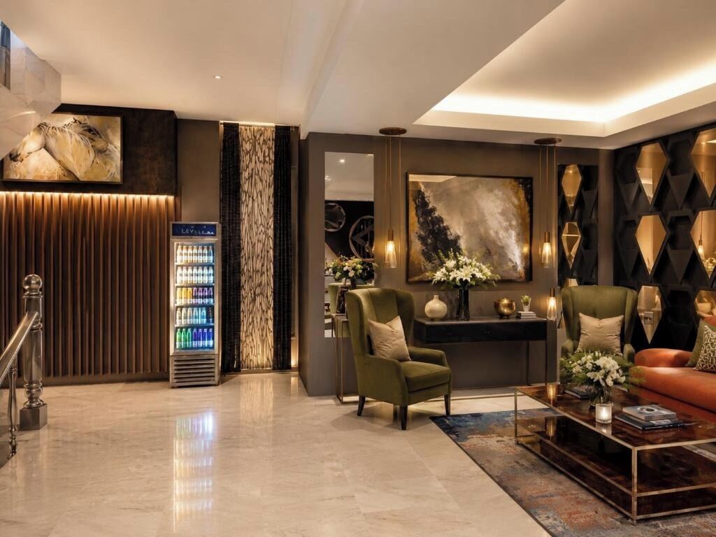 A modern lounge area with a sofa, armchairs, a coffee table, and a decorative wall.