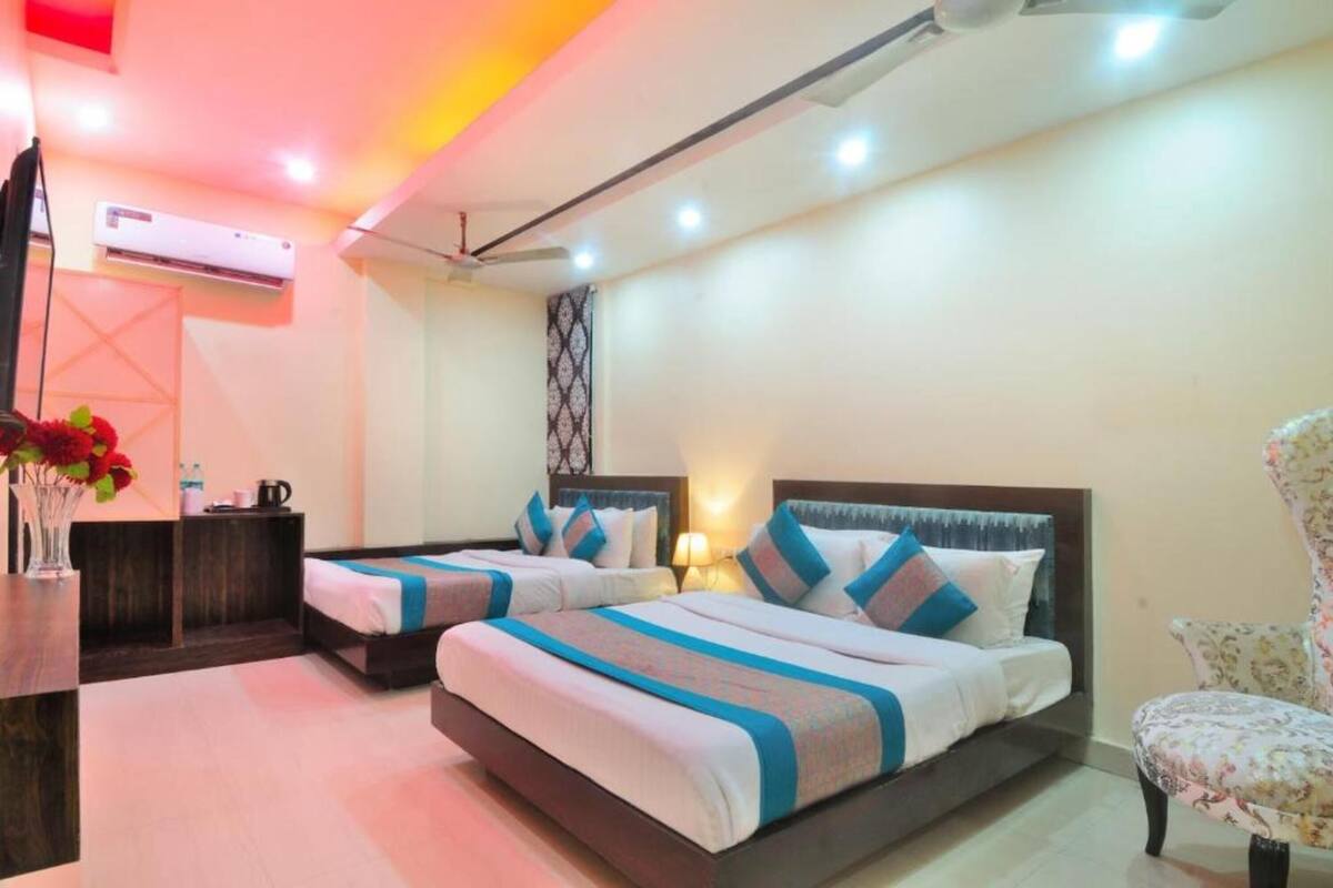 A hotel room with two beds, a desk, and an air conditioning unit.