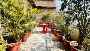 A hotel named "AIRA XING" with a red table and chairs in a garden area. - Staybook Hotel Aira  (New Delhi)