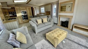 Ein gemütlicher Wohnbereich mit Sofa, Hocker und Küchenzeile.