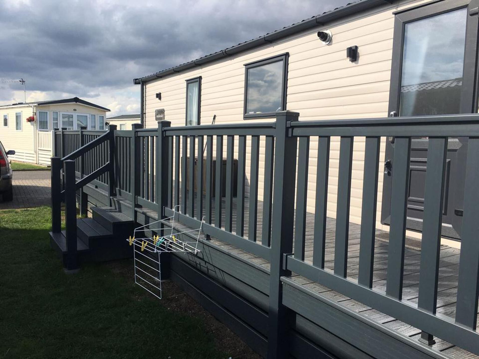 A row of mobile homes with a grey deck and a metal staircase leading to the entrance.