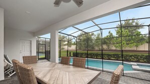 Eine überdachte Terrasse mit Pool, Korbmöbeln und Blick auf den Poolbereich.