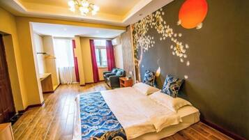 A hotel room with a large bed, a seating area with a chair and a table, and a wall with a decorative design.