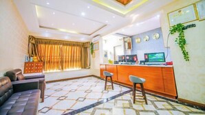 Een moderne hotellobby met een bank, een bar met krukken, een patroon vloer en een plafond met inbouwspots.
