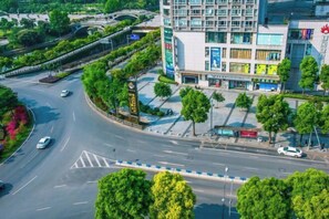 Un edificio moderno con una estructura de varios pisos, rodeado de vegetación y un camino curvo.