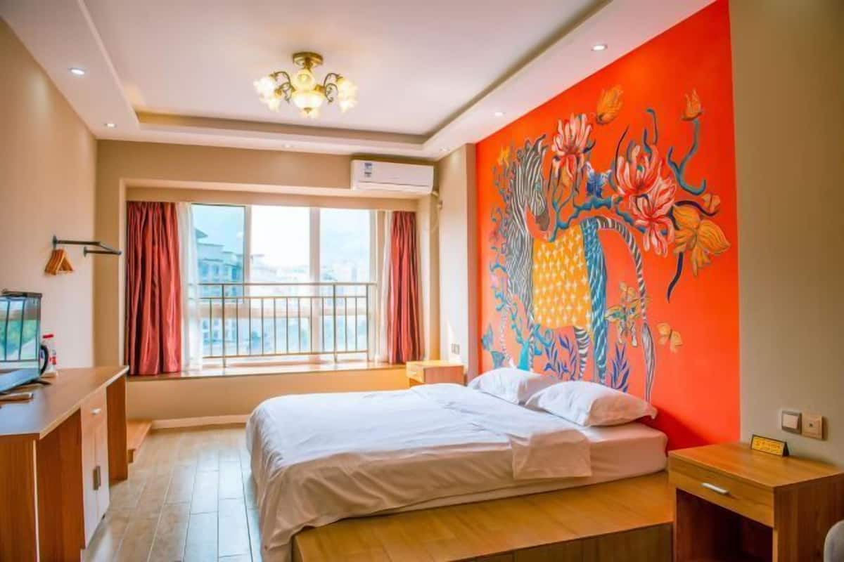 Une chambre d’hôtel avec un lit, un bureau et une grande fenêtre.