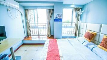 Quarto de hotel com cama, escrivaninha, televisão e janela com cortinas.
