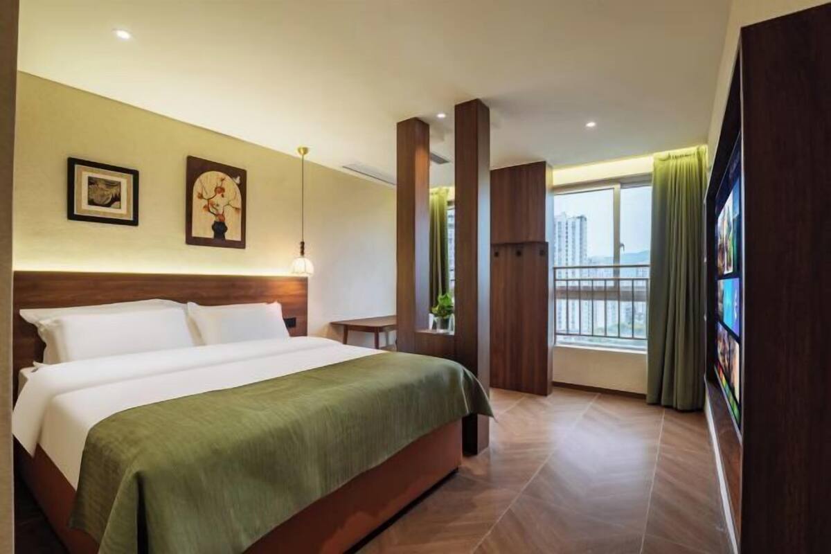 Une chambre d’hôtel avec un lit, des œuvres d’art au mur, une fenêtre avec des rideaux et un balcon.