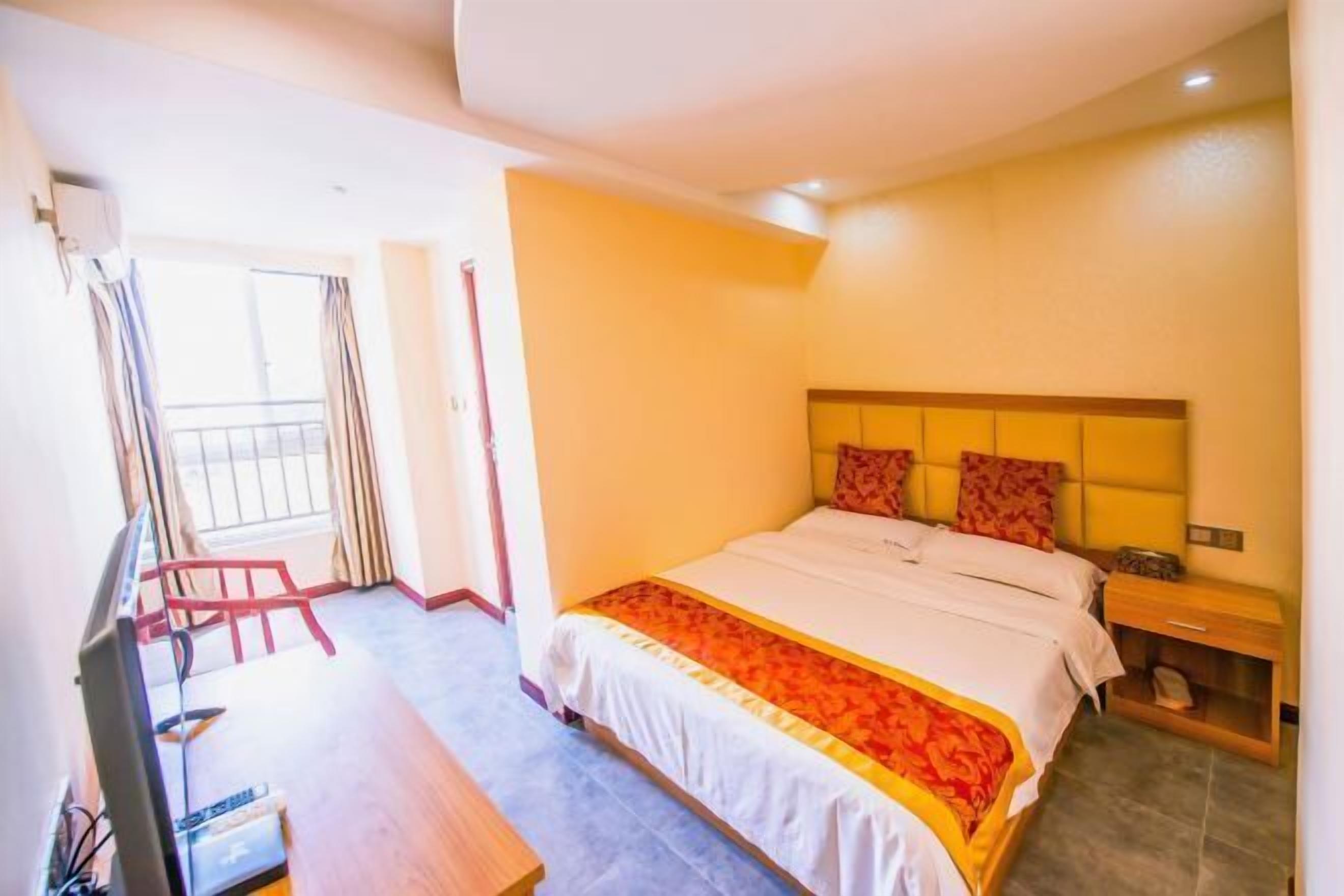 Ein Hotelzimmer mit Bett, Schreibtisch, Fernseher und einem Fenster mit Vorhängen.