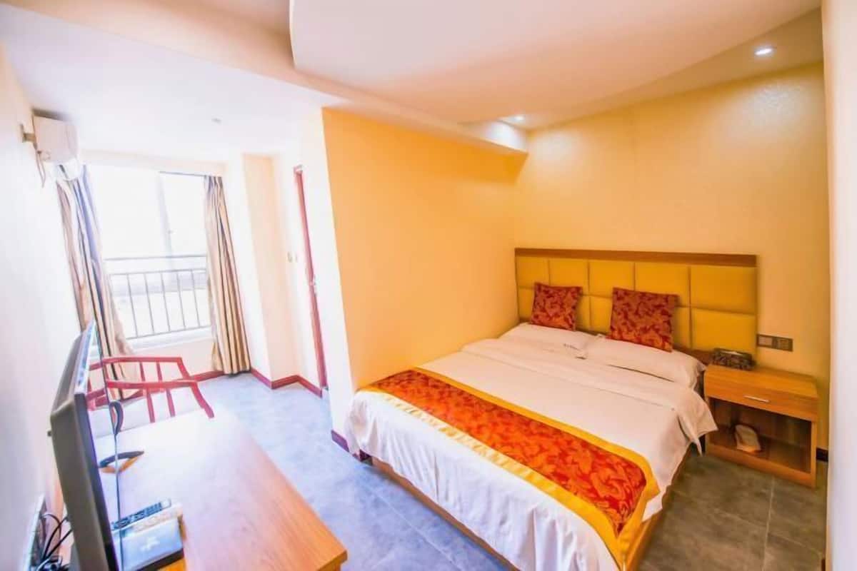 Une chambre d’hôtel avec un lit, un bureau, une télévision et une fenêtre avec des rideaux.