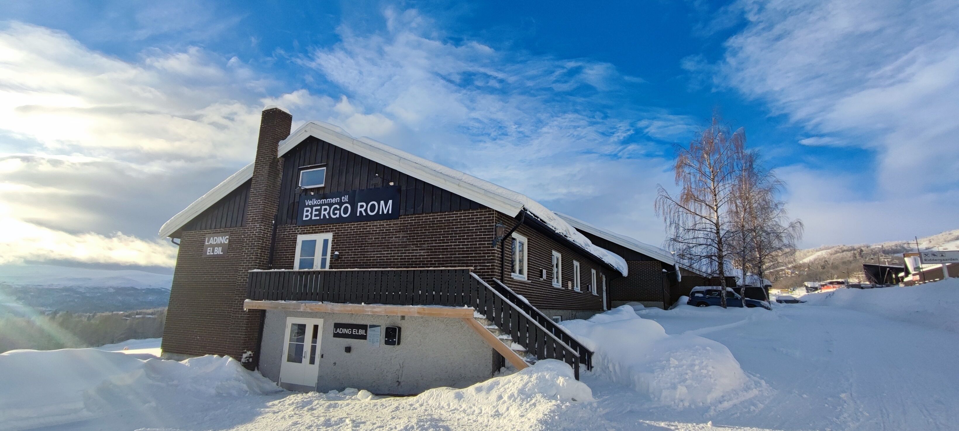 A wooden building with a sign reading "Welcome to BERGO ROM" and "LADING ELBIL".