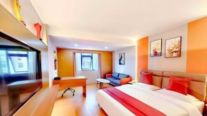 A hotel room with a bed, a desk, a TV, a sofa, and artwork on the walls. - Grandhall Hotel Shishi (Shishi)