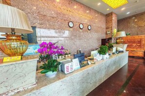 A marble reception desk with a lamp, a clock, and a plant. - Grandhall Hotel Shishi (Shishi)