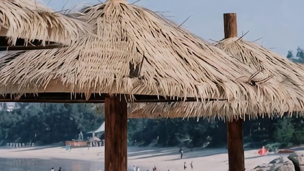 A beach with thatched umbrellas and a wooden structure. - Grandhall Hotel Shishi (Shishi)