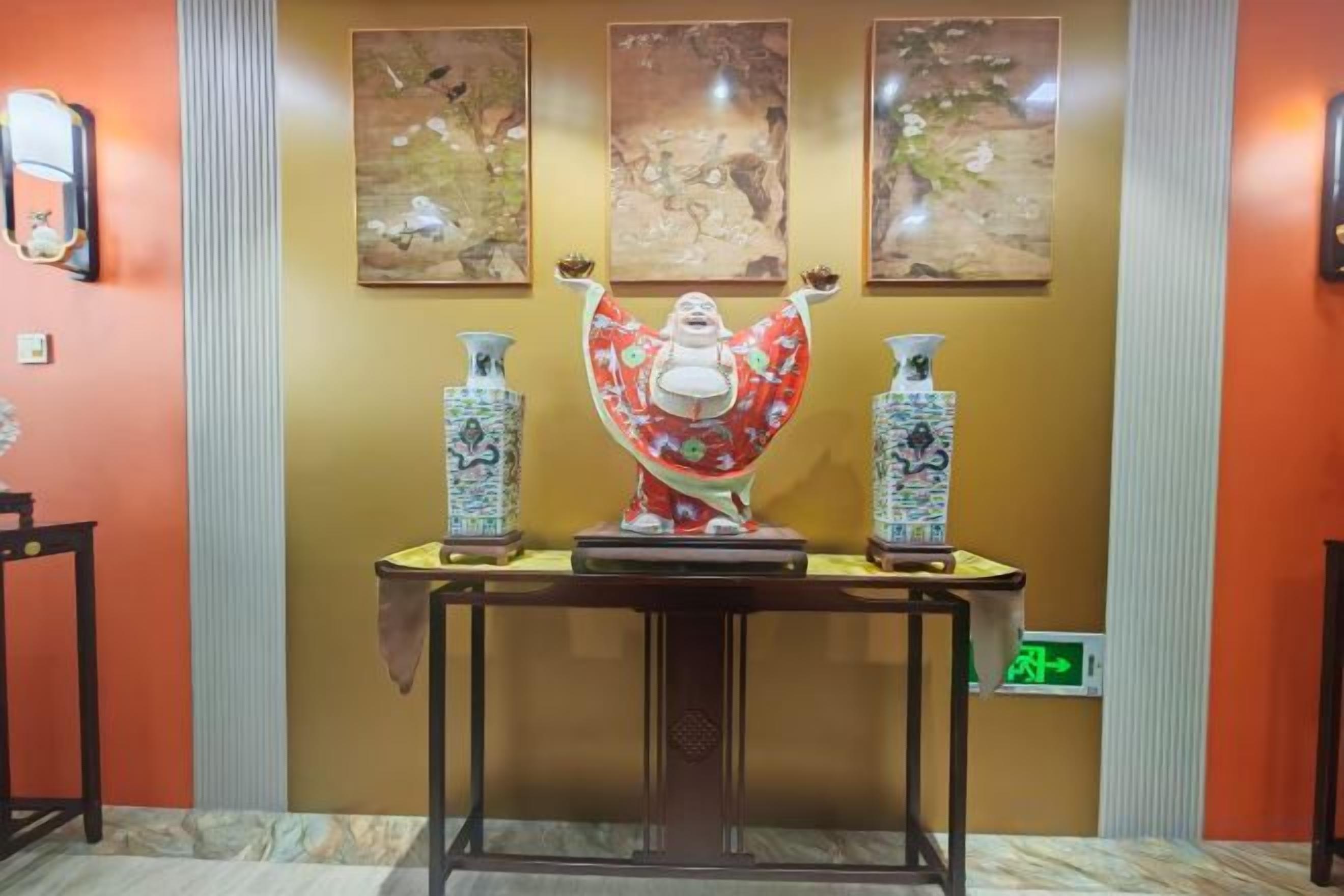 Una habitación con una mesa que exhibe jarrones tradicionales y una estatua.