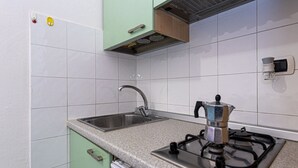 A kitchen with a gas stove, stainless steel sink, and light green cabinets. - Casa Bartolomea - CASA BARTOLOMEA 9 (Marina di Campo)