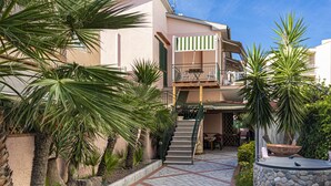 A two-story building with a balcony, a stone-tiled courtyard, and various potted plants. - Casa Bartolomea - CASA BARTOLOMEA 9 (Marina di Campo)