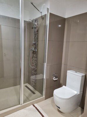 A modern bathroom with a glass-enclosed shower, a toilet, and a tiled floor. - Lovely Furnished 1-bed Apartment in East Legon (Accra)