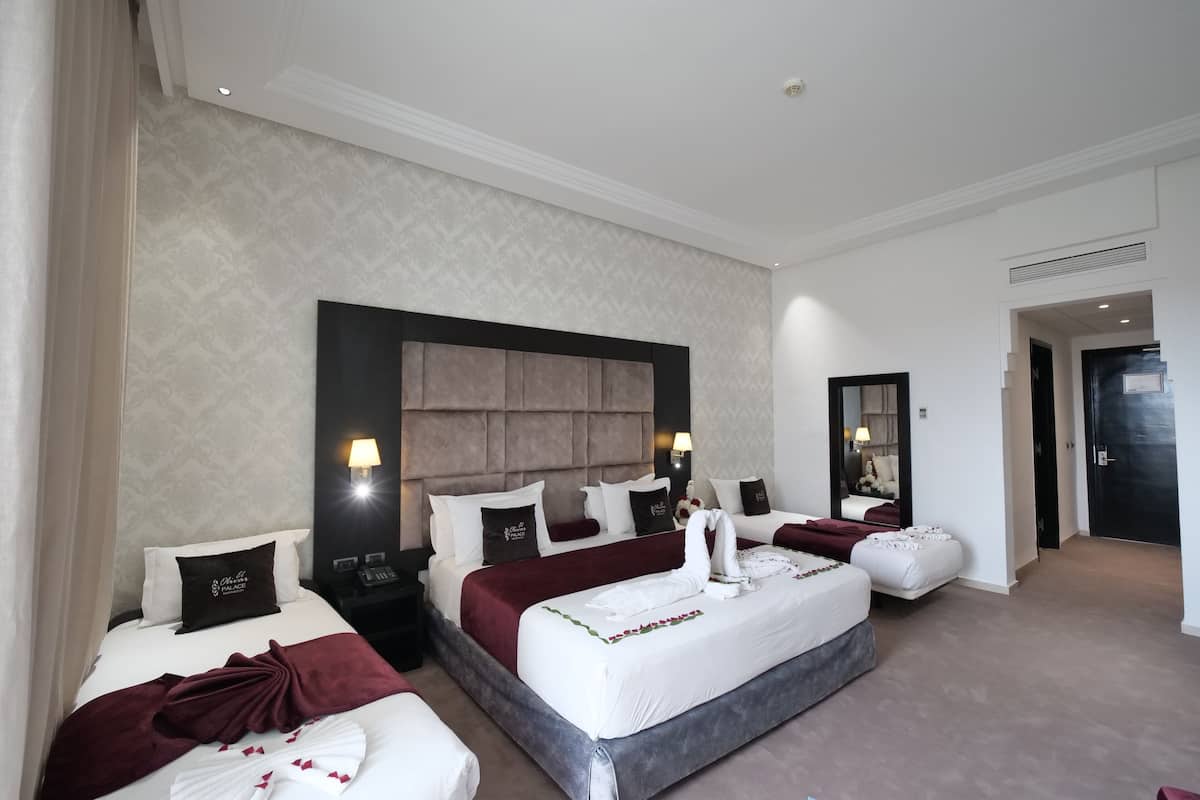 A hotel room with two beds, a large headboard, and a mirror.