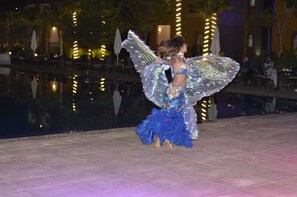 Una persona vestida con un traje azul y plateado actuando junto a una piscina.