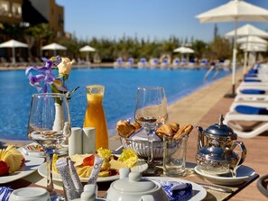 A breakfast buffet with various food items and drinks, a pool in the background, and lounge chairs along the poolside. - El Olivar Palace Marrakech All Inclusive, Aquapark &amp; SPA (Marrakech)