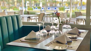 Un ambiente de restaurante con una mesa dispuesta para dos personas, que incluye copas transparentes, servilletas y cubiertos.