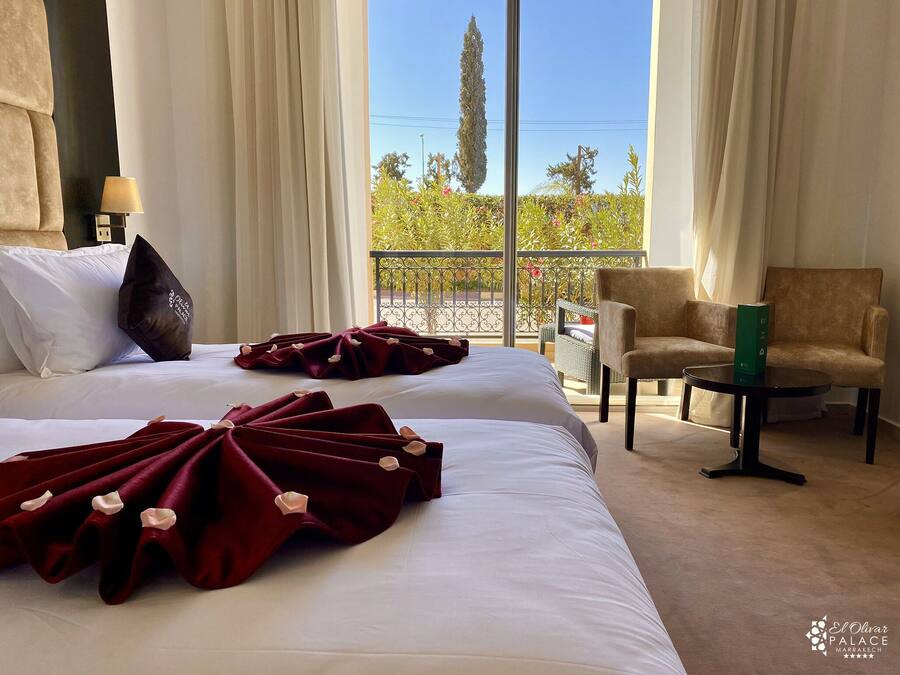 Habitación de hotel con dos camas, un balcón, una silla y una mesa.