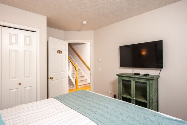 A bedroom with a bed, a television on a cabinet, a door, and a staircase. - Promo! Oceanfront Condo with Indoor Pool, Wifi and HDTV! (Depoe Bay)