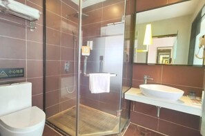A modern bathroom with a glass-enclosed shower, a white sink, and a large mirror.