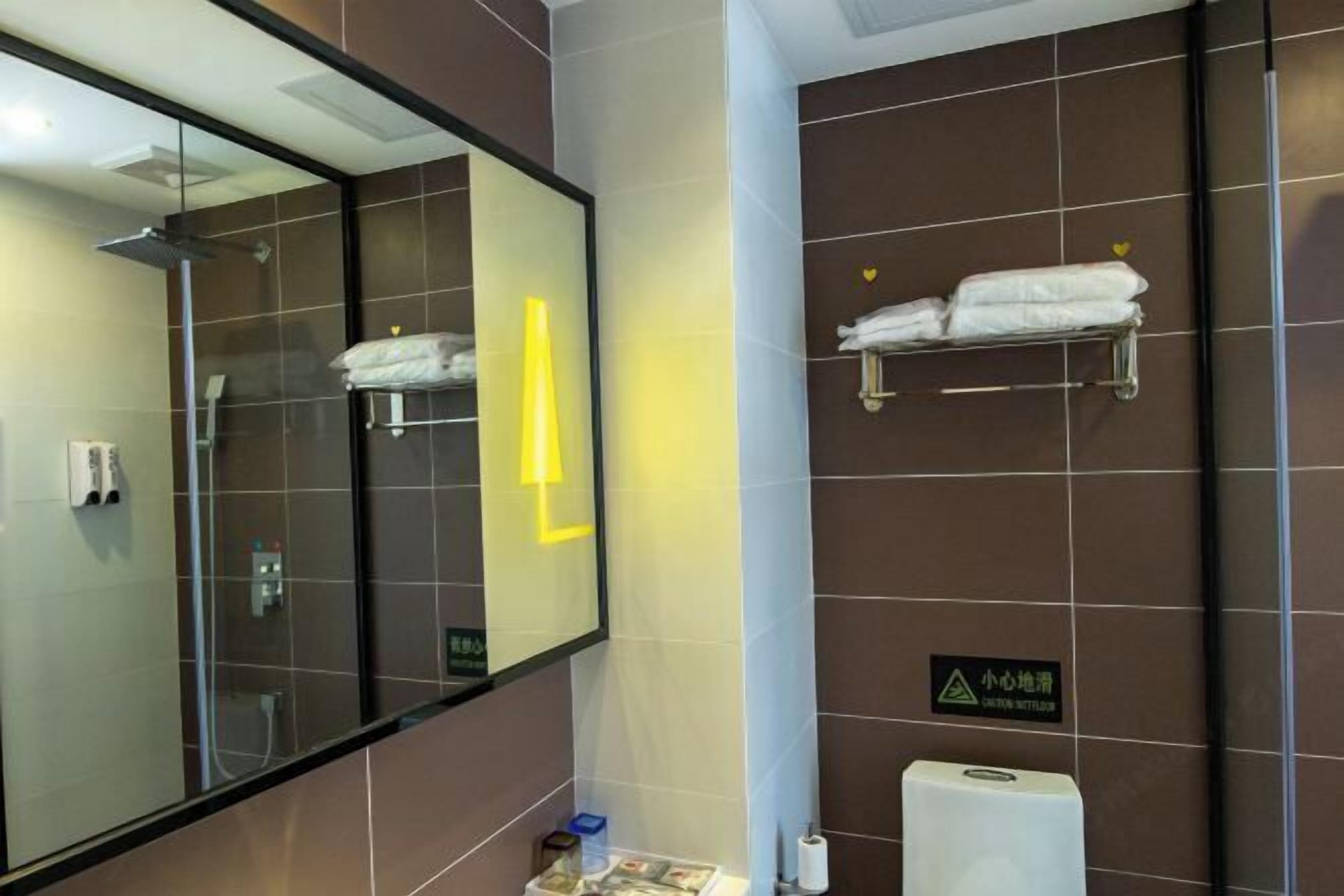 A modern bathroom with a large mirror, a towel rack, and a hand dryer.