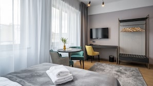 Ein Hotelzimmer mit Bett, Schreibtisch, Stuhl, Fernseher und Kleiderschrank.