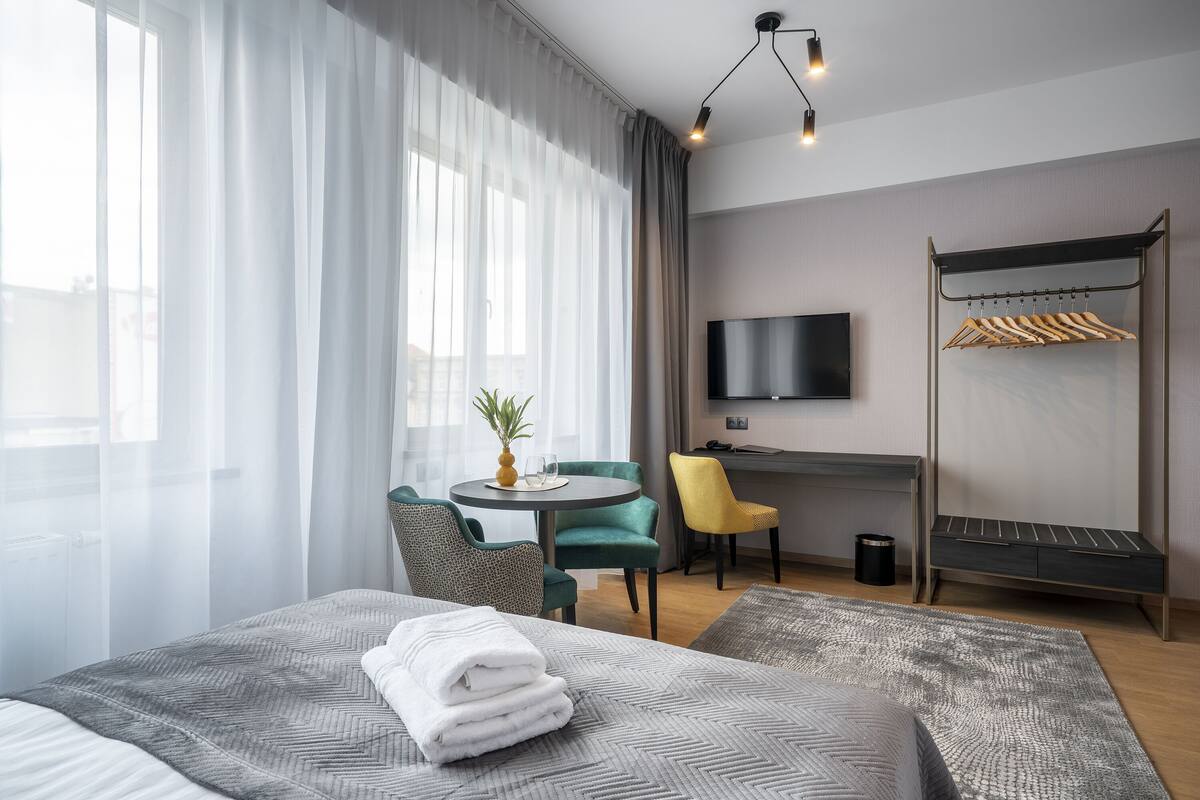 Hotellihuone, jossa on sänky, työpöytä, tuoli, televisio ja vaatekaappi.