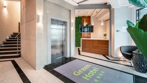 Eine moderne Hotelhalle mit einer Rezeption, einer Treppe und einer grünen Wand.